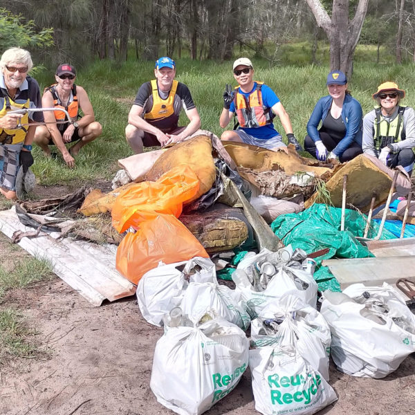 SSCC Volunteers crouch behind pile of collected rubbish